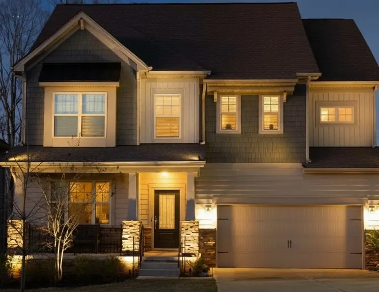 Same house at night with lights on, warmly lit